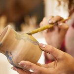 Close up, girl paints a vase before baking